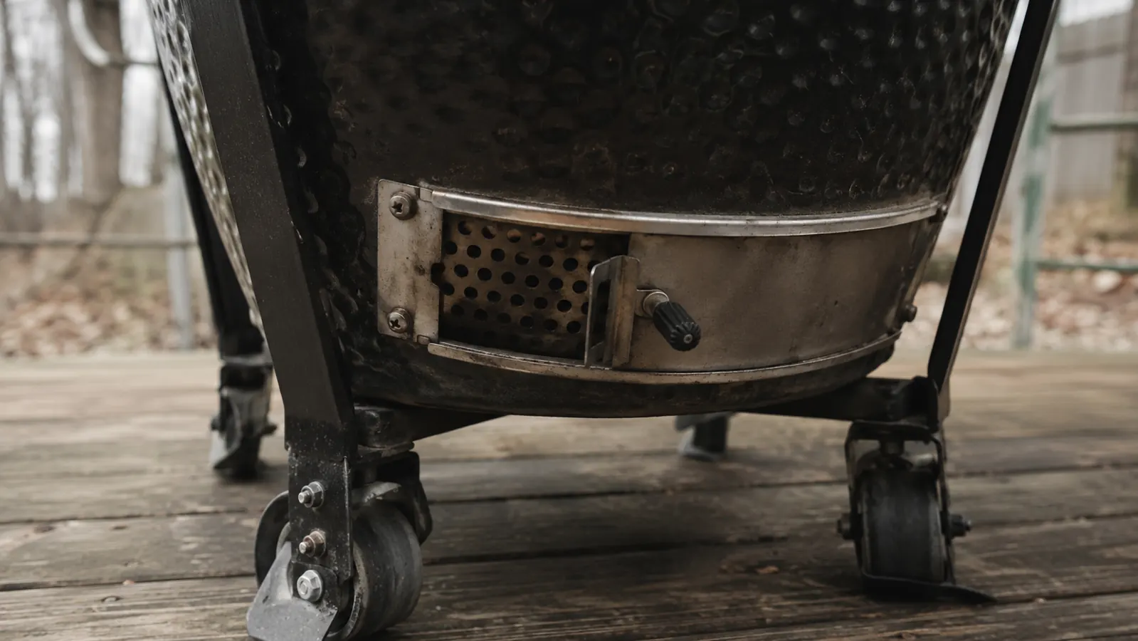 Close view of the Char-Griller AKORN's cracked plastic vent wheel and worn felt gasket on an overcast afternoon